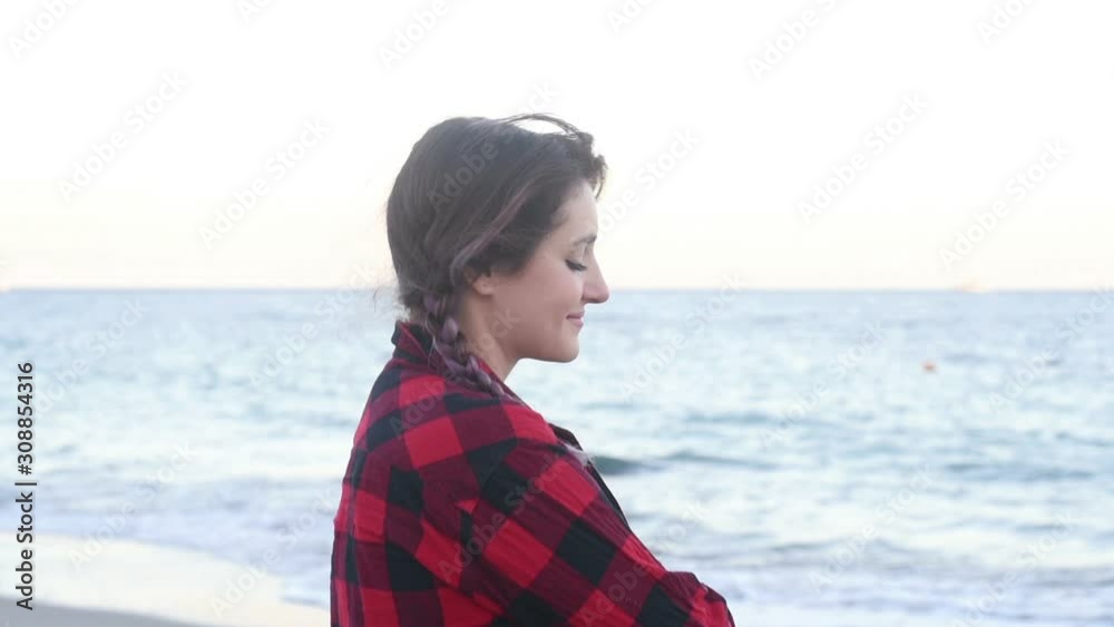 Girl with purple pigtails in a plaid shirt and black leather jacket walking along the seashore Girl with purple pigtails in a plaid shirt and black leather jacket walking along the seashore