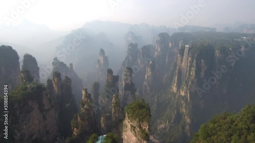 Drone footage of tall rock pillars with moving Bailong elevator in the background in Zhangjiajie National Forest Park also known as Wulingyuan Scenic Area in China. 
