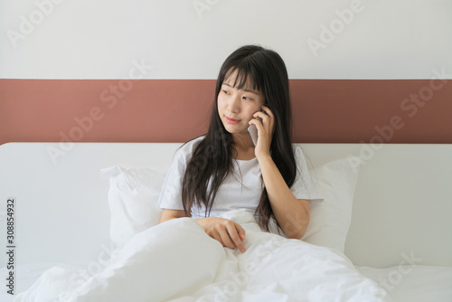 asian young woman making phone call on bed