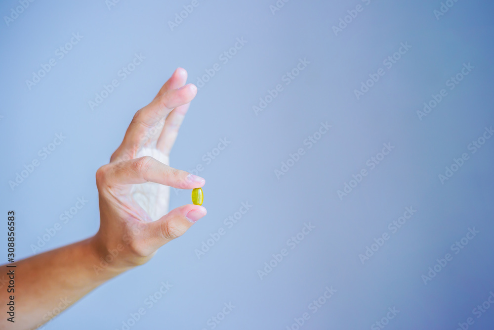 Close up photo of one round yellow pill in hand. Man takes medicines with glass of water. Daily norm of vitamins, effective drugs, modern pharmacy for body and mental health.