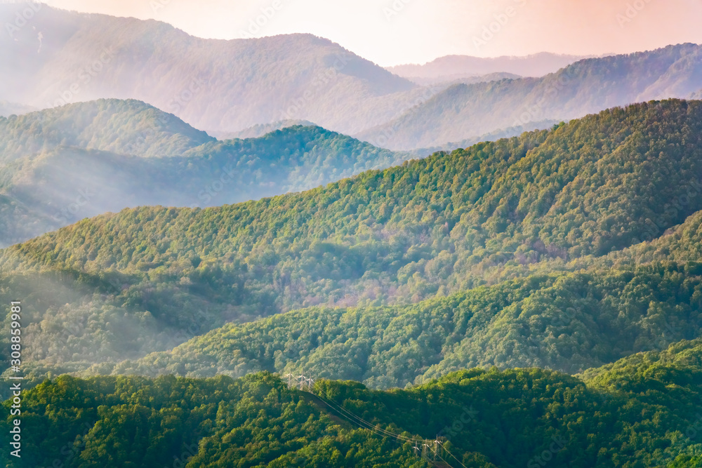 Fototapeta premium Layers of mountains in the haze during sunset. Beautiful sunset in the hills and mountains. Beautiful sunset in a hilly valley with fog in the lowlands.