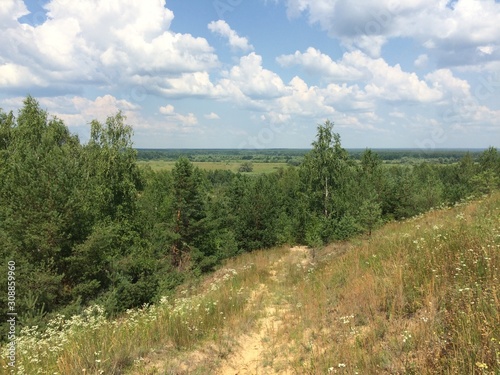 View from the mountain to the landscape under the blue sky with white clouds and going into the ravine narrow path. Mobile photo in natural daylight.