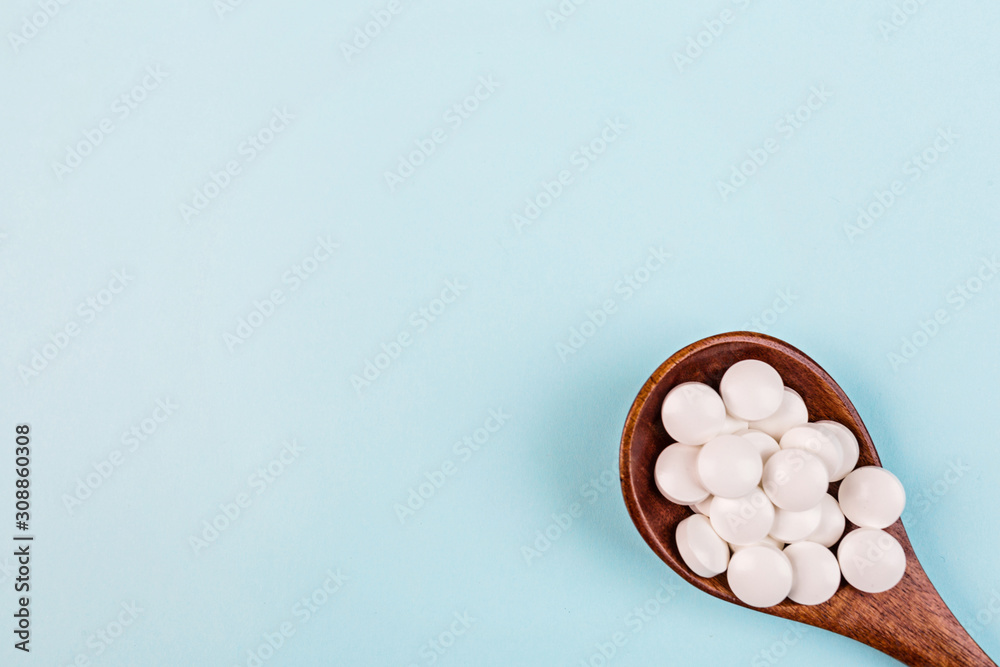 White pills in spoon on a pastel blue background. Flat lay, top view, overhead, mockup, template, copy space. Pharmacy and medical concept White pills in spoon on a pastel blue background. Flat lay, top view, overhead, mockup, template, copy space. Pharmacy and medical concept