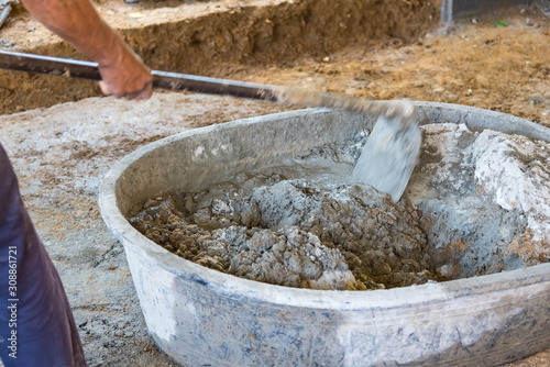 Worker Mixed Cements in Basin Mixer with Hoe in construction site.