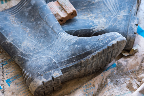 Dirty rubber boots of workers in the construction site. © bubbers