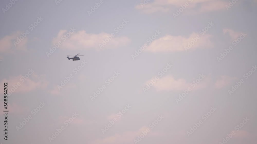 Military helicopter flies past clouds in pink sunset sky Military helicopter flies past clouds in pink sunset sky