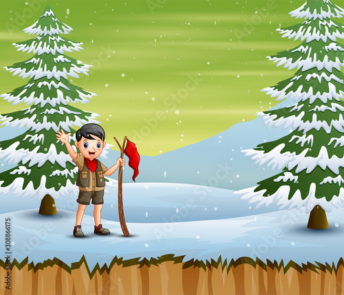 Explorer boy with red flag standing in winter landscape