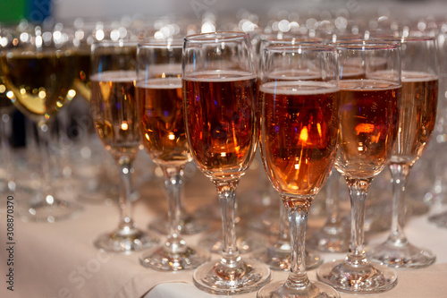 Rows of glasses with pink champagne on a festive buffet table. Exit registration of events. Close-up.