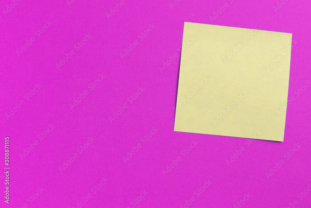 Square yellow sticker note on a bright pink background close up Square yellow sticker note on a bright pink background close up