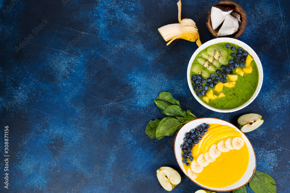 Two cups of different smoothie bowl of green and yellow fruits. The concept of healthy eating. Horizontal photo with copy space. Top view.