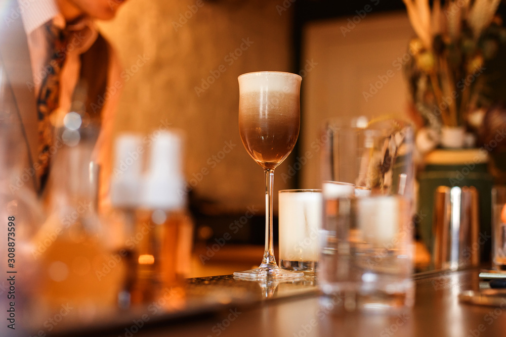 An espresso martini cocktail on the bar counter. Warm lifestyle image, selective focus, natural light