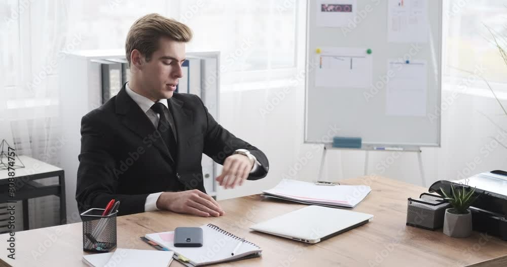 Businessman texting on mobile phone after finishing his work on office laptop Businessman texting on mobile phone after finishing his work on office laptop