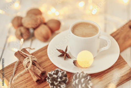 Cozy autumn or winter concept. Cup of coffee with a garland lights and decoration/