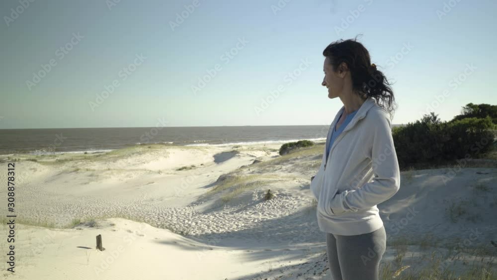 Athlete woman standing on sand dune in the beach Athlete woman standing on sand dune in the beach
