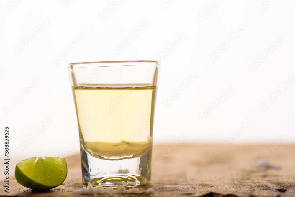 Vodka in a shot glass on a brown wooden background prepared for a party Vodka in a shot glass on a brown wooden background prepared for a party