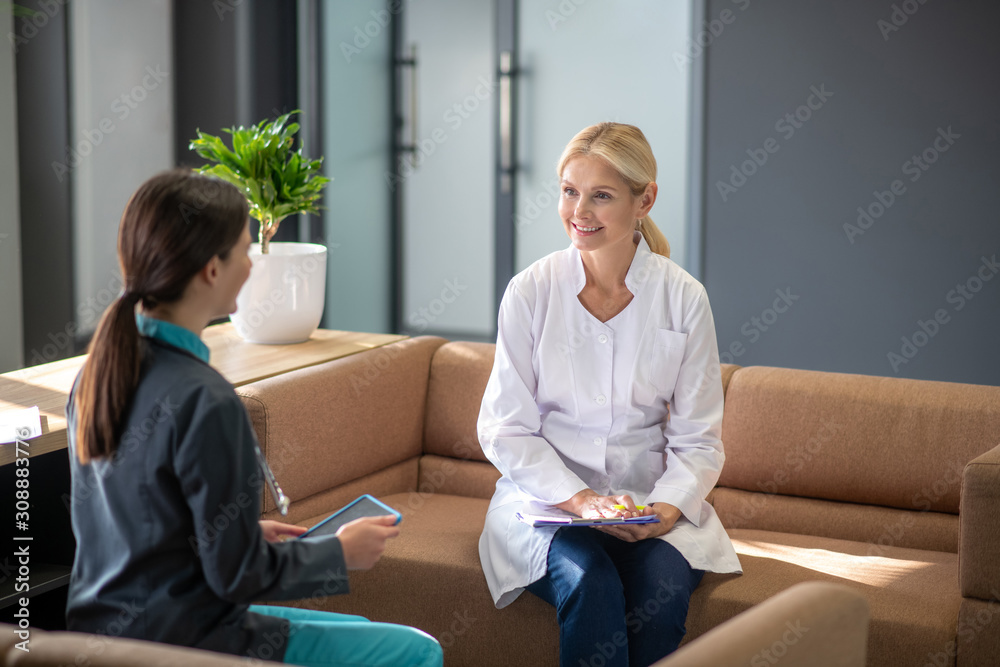 Dark-haired young female and her senior friend talking positively Dark-haired young female and her senior friend talking positively