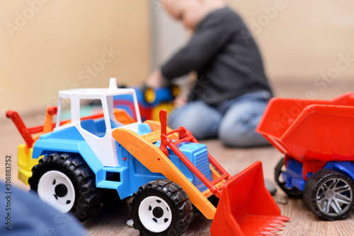 Colorful toy tractor on the floor in the room.