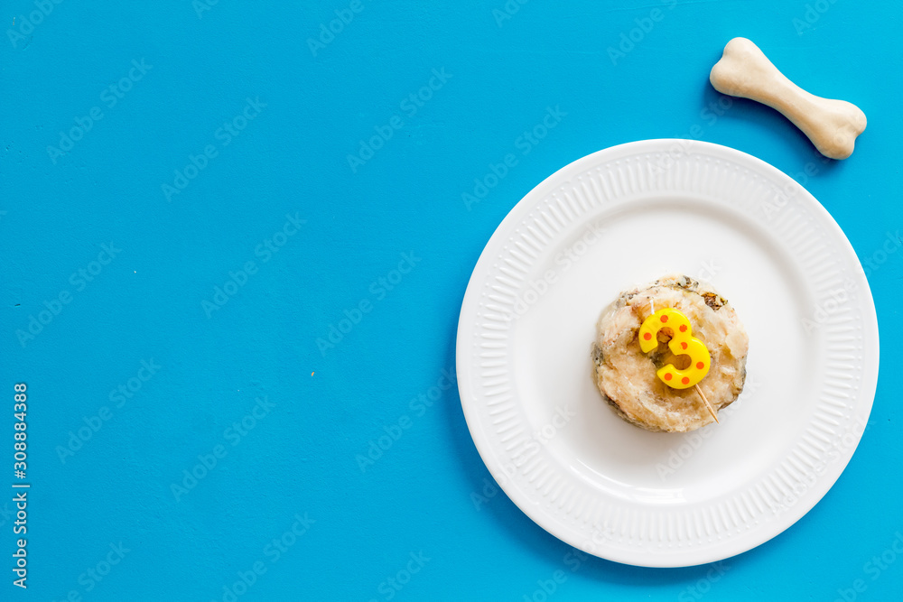Birthday treat for puppy concept. Dog feed, candle in shape of number three, bones on blue background top-down copy space Birthday treat for puppy concept. Dog feed, candle in shape of number three, bones on blue background top-down copy space