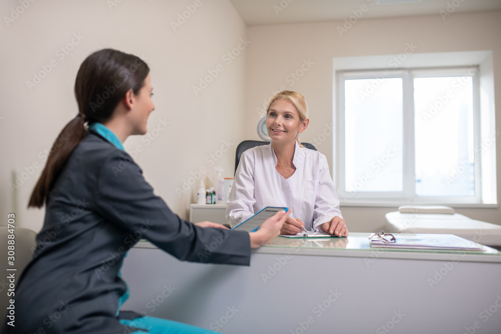 Two female doctors sitting at the table in the office Two female doctors sitting at the table in the office