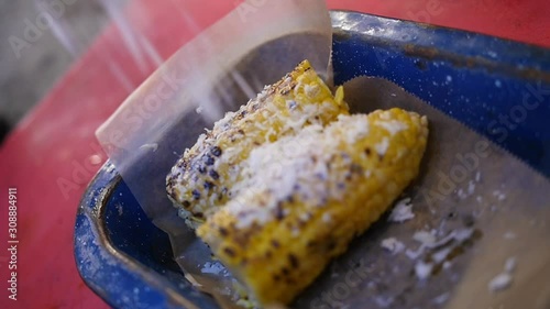 Close up of a chef garnishing the tasty corn on the cob with grated cheese photo