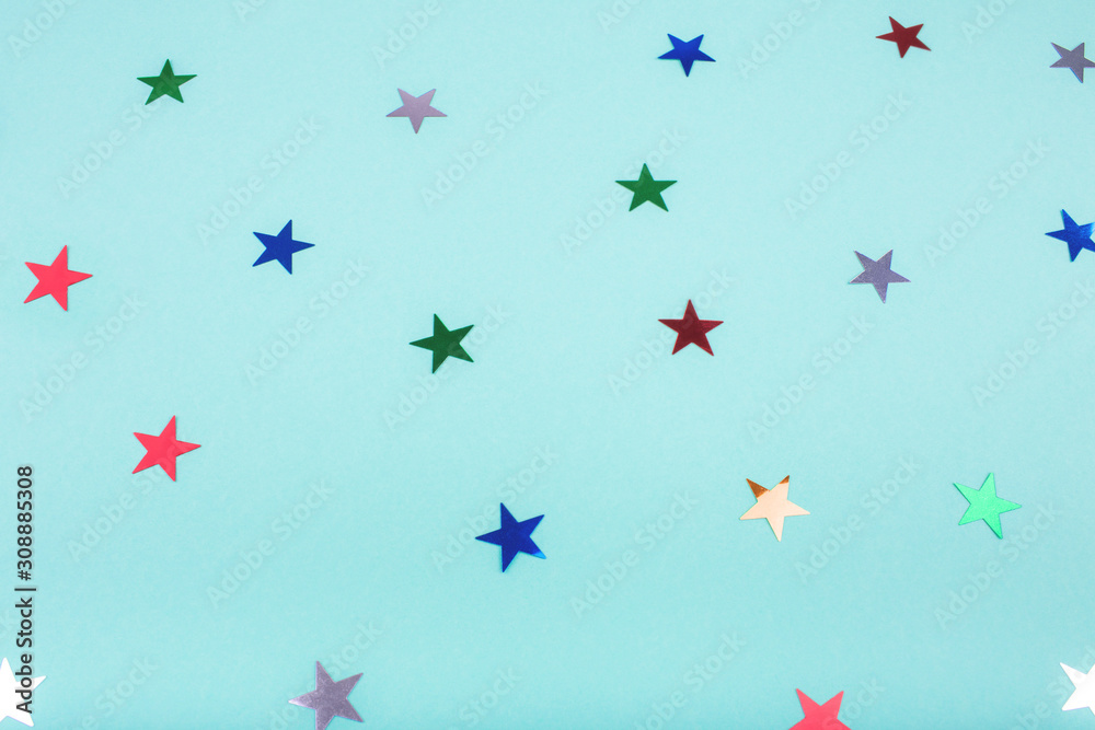Multicolored, glitter stars on mint color background. For Christmas and New year day. Copyspace for text. Top view, flat lay. Holiday backdrop.