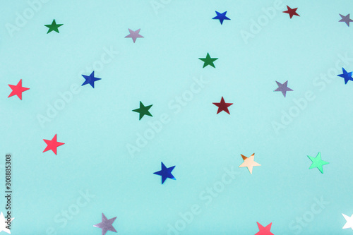 Multicolored, glitter stars on mint color background. For Christmas and New year day. Copyspace for text. Top view, flat lay. Holiday backdrop.
