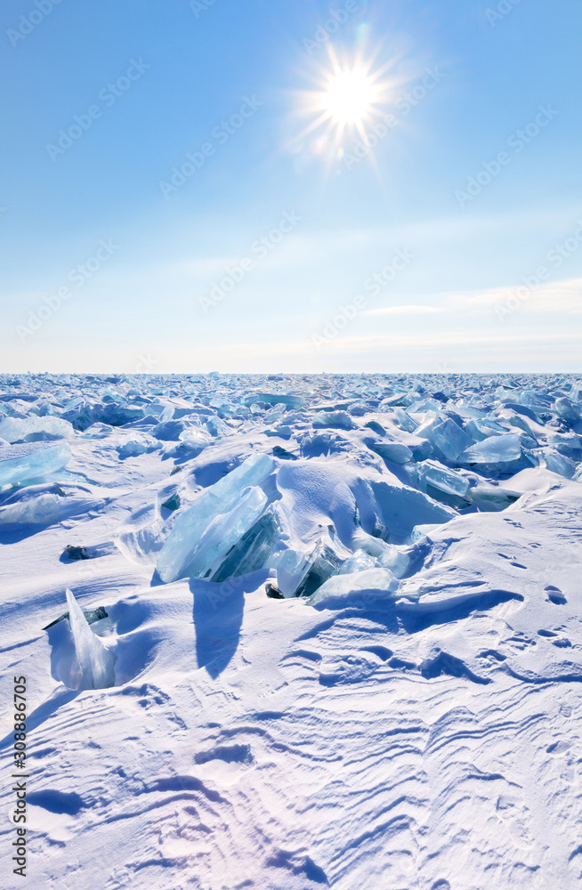 Baikal Lake on a February frosty day. The sun over a snowy field of ice hummocks. Winter extreme tourism. Natural phenomenon, cold background Baikal Lake on a February frosty day. The sun over a snowy field of ice hummocks. Winter extreme tourism. Natural phenomenon, cold background