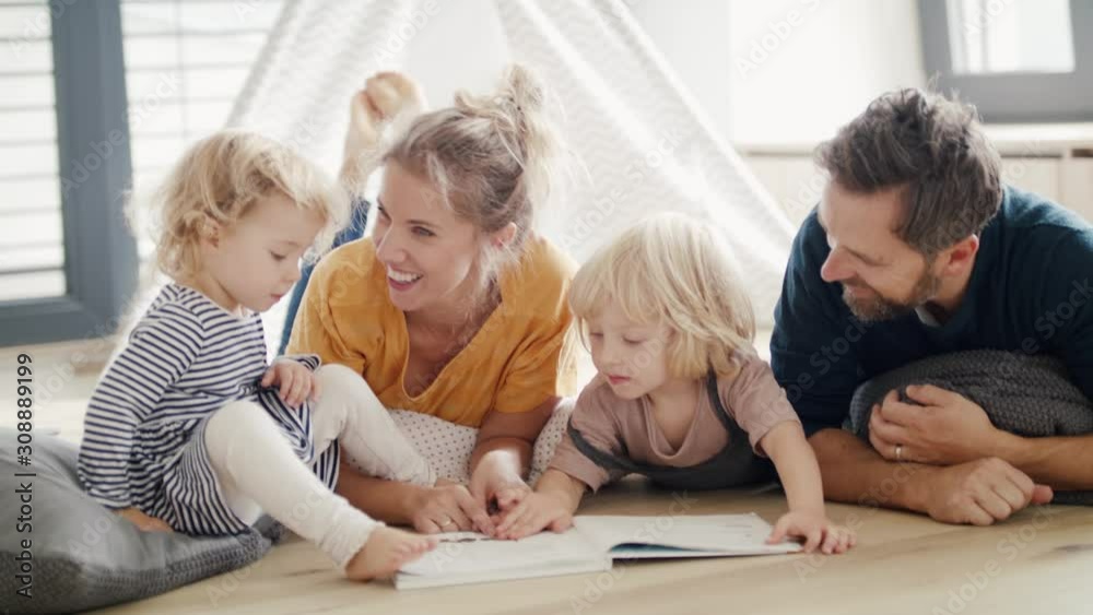 Young family with two small children indoors in bedroom reading a book. Young family with two small children indoors in bedroom reading a book.
