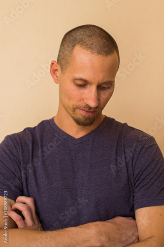 Portrait of a brooding young man in a blue or purple photoball against a beige wall