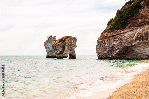 Famous sea stacks of Baia delle Zagare bay in Gargano National park. Natural rock sculptures made by Adriatic sea waves, wind and erosion stacked in the sea near the rocky beach