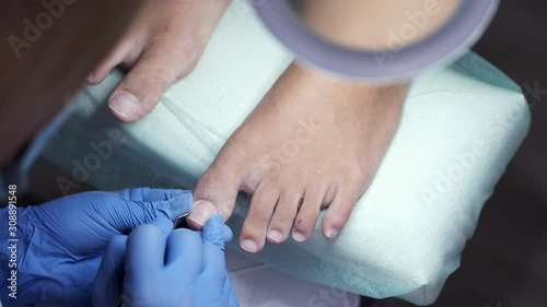 The pedicure master is polishing nails. There is a LED lamp here. The customer's feet are on the special pillow. photo