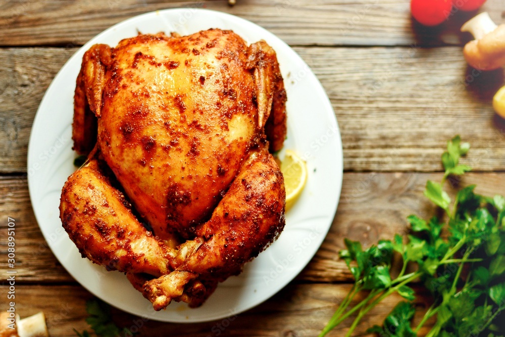 Whole baked chicken curry with golden crisp. Baked chicken on a wooden background. Whole baked chicken curry with golden crisp. Baked chicken on a wooden background.