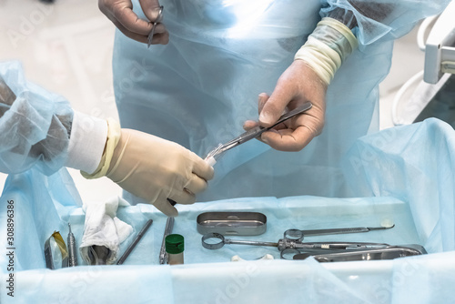 Close-up of the hands of a dentist surgeon on implantation, with dental instrument and surgical template