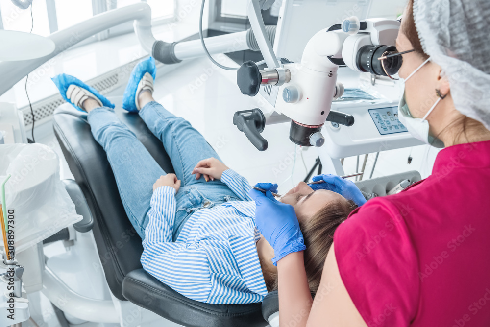 The dentist examines the patient with a microscope in the dentist's office The dentist examines the patient with a microscope in the dentist's office