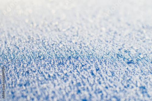 Texture of sparkling first cold ice. Blue snowy backdrop. Winter background for design. Abstraction in nature.