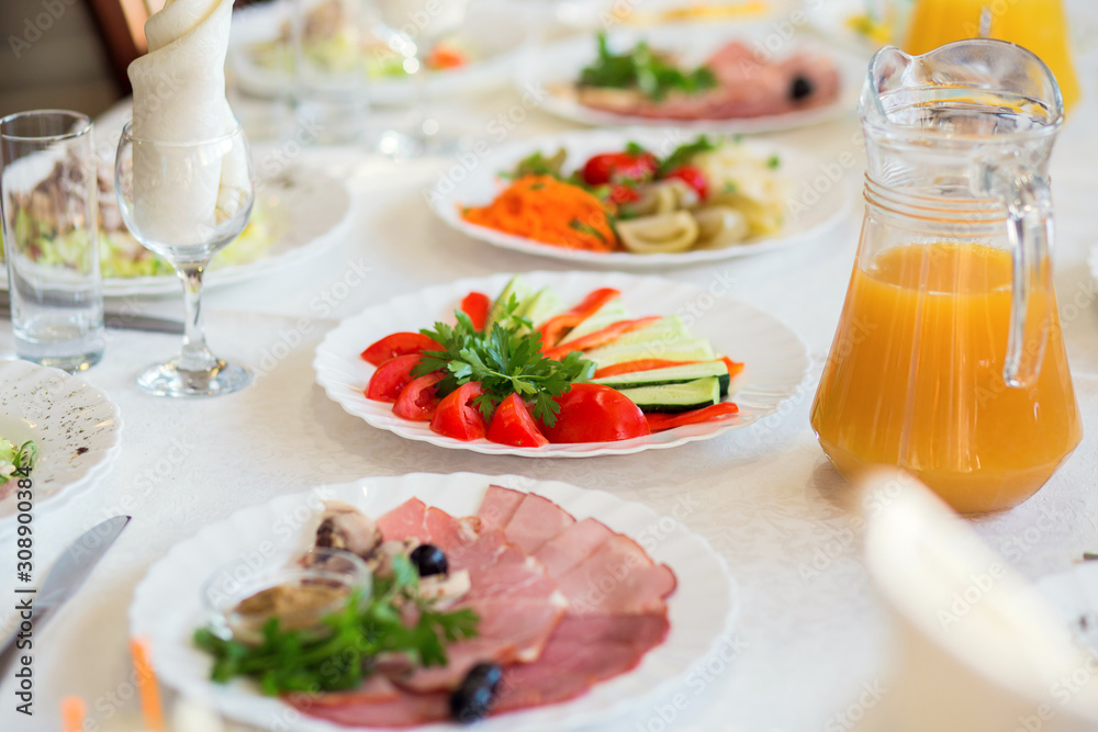 Sliced vegetables and cold cuts on a plate served on a table in a restaurant for a banquet