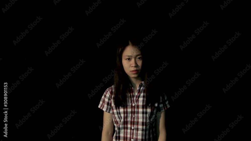 Sad girl wearing smiling mask in the dark. Depression disguise in happiness concept. Sad girl wearing smiling mask in the dark. Depression disguise in happiness concept.