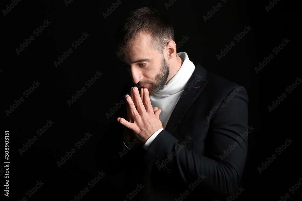 Portrait of praying young man on dark background Portrait of praying young man on dark background