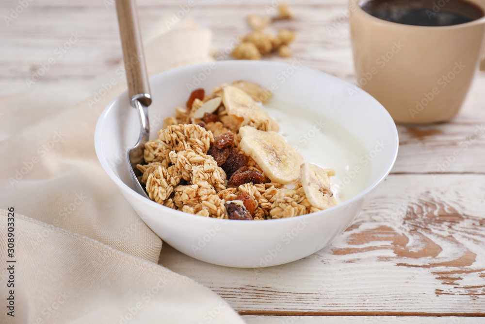 Tasty granola with yogurt in bowl on wooden table Tasty granola with yogurt in bowl on wooden table