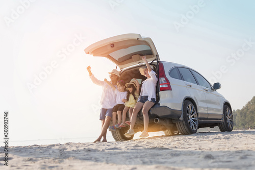 Cheerful parents, children are playing on the sandy beach with happiness in summer.