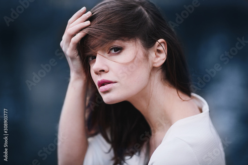 Charming young woman with dark hair and a beautiful neck in autumn park. Deep pensive look.