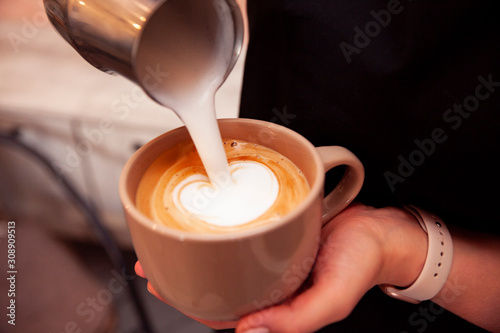 Barista pours milk into a cup of coffee