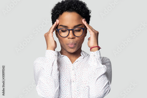 Tired millennial ethnic girl suffering for strong headache.