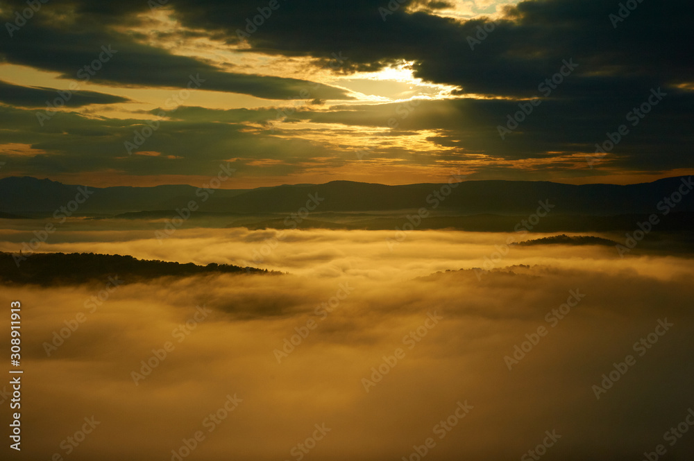 The dawn sun illuminates the fog in the mountains.