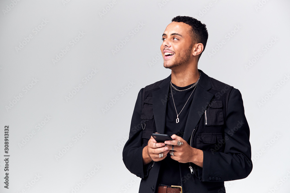 Studio Shot Of Causally Dressed Young Man Using Mobile Phone Looking Off Camera Studio Shot Of Causally Dressed Young Man Using Mobile Phone Looking Off Camera