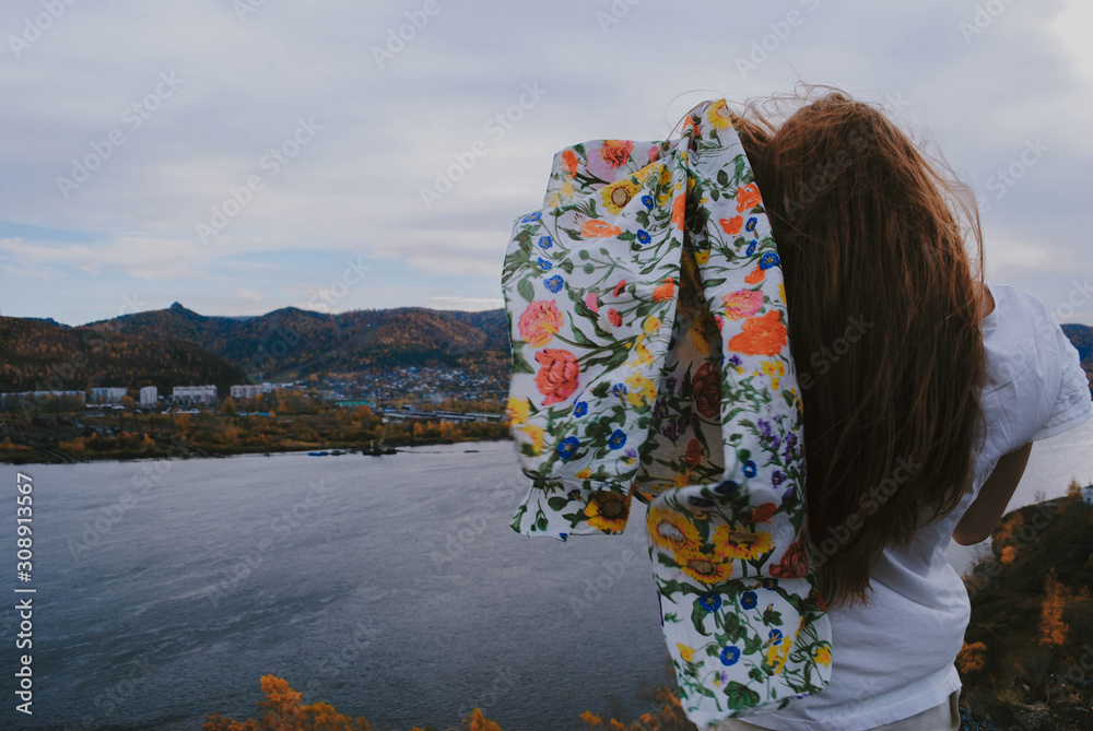 Red-haired girl in the fall on the background of the Yenisei river and mountains Red-haired girl in the fall on the background of the Yenisei river and mountains