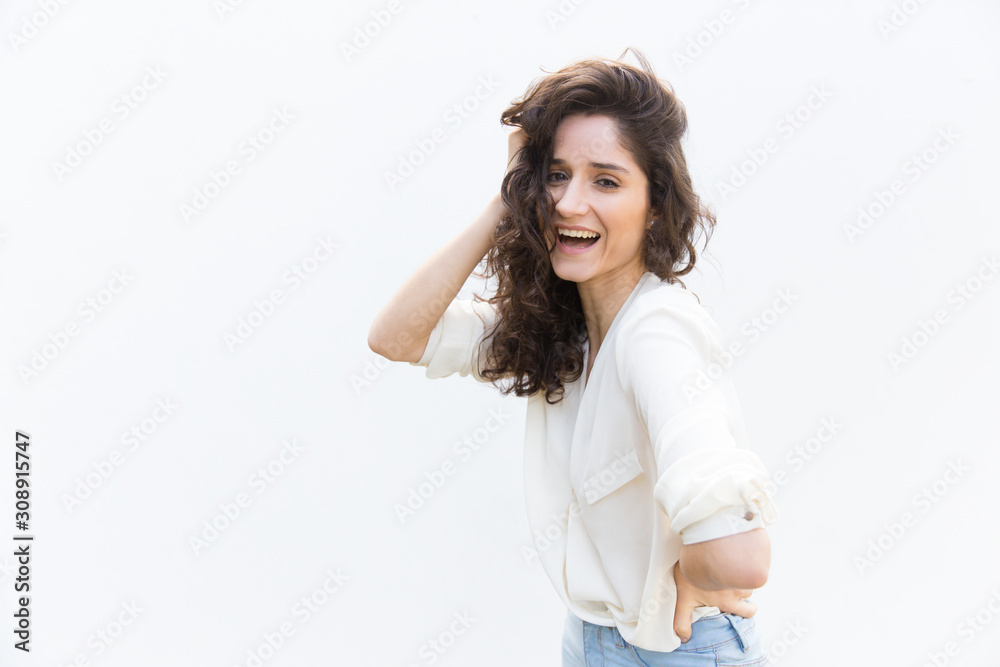 Happy joyful woman touching curly hair and laughing at camera. Wavy haired young woman in casual shirt standing isolated over white background. Advertising concept Happy joyful woman touching curly hair and laughing at camera. Wavy haired young woman in casual shirt standing isolated over white background. Advertising concept