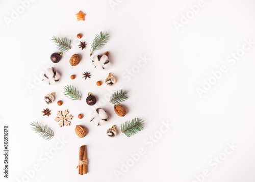 Creative christmas tree made of New years decorations, spruce, cotton, nuts, cinnamon on white background.