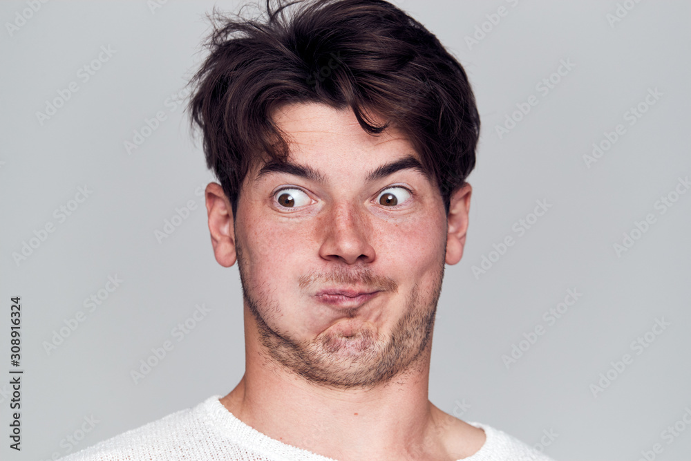 Obraz premium Head And Shoulders Studio Shot Of Man Pulling Faces And Smiling At Camera