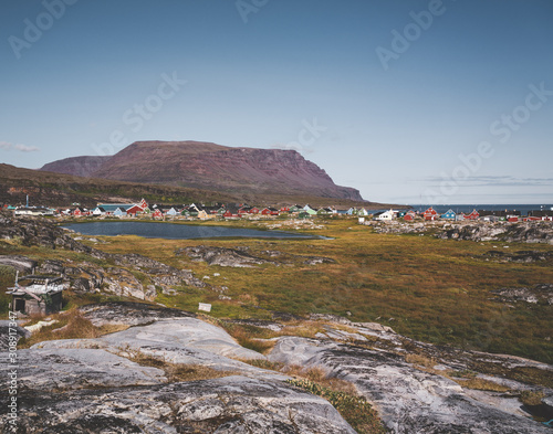 View over colourful greenland houses of Disko Island, arctic city of Qeqertarsuaq. Located in the disko bay. Blue sky and sunny day. Table mountains in Background. photo